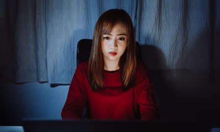 Asian woman working late at night with laptop computer home office looking screen monitor unhappy...