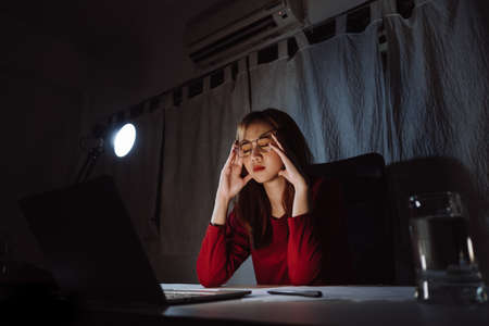 Asian woman working late at night with laptop computer home office looking screen monitor stressed work hard, Freelancer stay home business sleepless quarantine crisis coronavirus stay home dark room.の写真素材