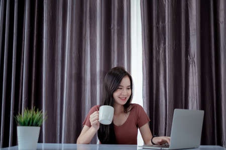 Asian woman working from home with laptop computer self isolation from society to reduce risk, quarantine prevention coronavirus, covid-19 and study e-learing online education technology concept.の写真素材