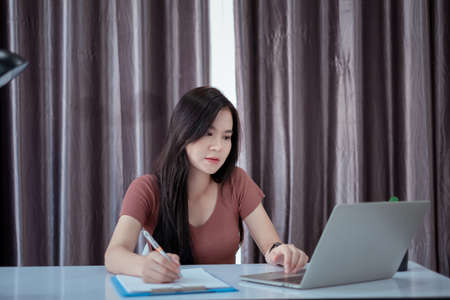 Asian woman working from home with laptop computer self isolation from society to reduce risk, quarantine prevention coronavirus, covid-19 and study e-learing online education technology concept.の写真素材