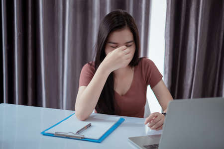 Asian woman wokring from home office overworked stressed deadline on laptop computer unhappy emotion...