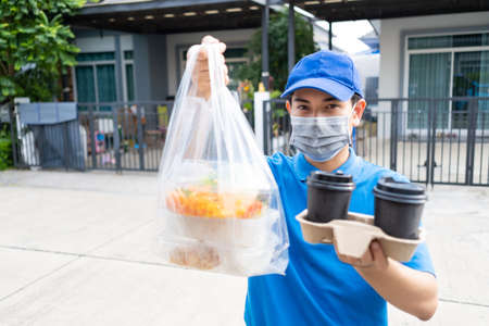 Food Delivery man wearing mask handing plastic bags shopping online from supermarket to client service customer front house, express grocery when coronavirus covid19 new normal lifestyle.の写真素材