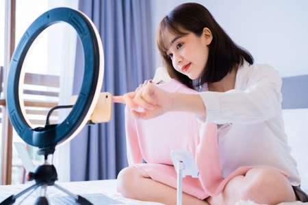 Beautiful Asian woman vlogger recording dressing up of clothes hanging on a hanger in the wardrobe,...