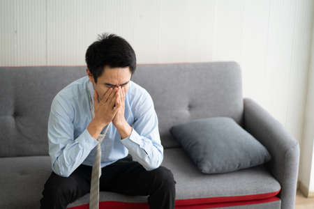 Businessman strain economic problem during Coronavirus.He sitting on sofa in the hospital. Doctor explaining to young patient his health problem.の写真素材