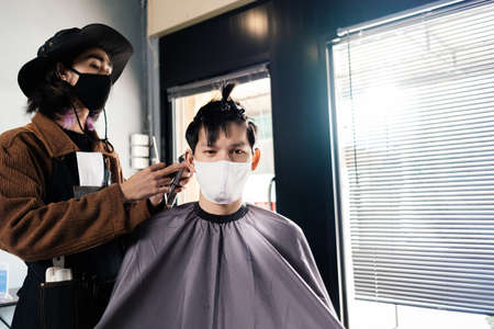 Asia Barber Shop Hair cut queueing customer's wearing face mask prevention business reopening after covonarirus lockdown, Men's hairstyling and new normal lifestyle concept.の写真素材
