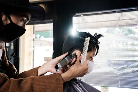 Asia Barber Shop Hair cut queueing customer's wearing face mask prevention business reopening after covonarirus lockdown, Men's hairstyling and new normal lifestyle concept.の写真素材