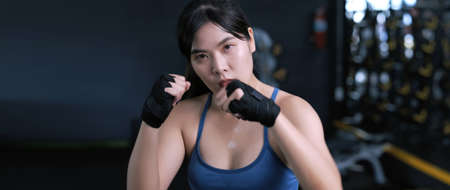 Sporty young asian women boxer wearing strap on wrist, Woman in sports preparing for boxing fight practice or workout. Athlete fit in a gym training. Exercises banner size with copy space panoramic.の写真素材