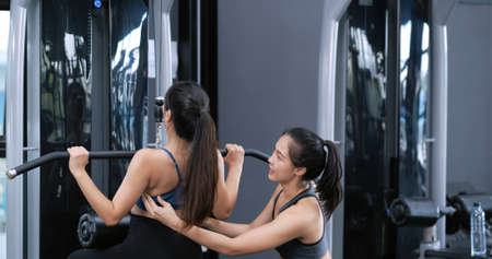 Bodybuilder of women training exercise workout at fitness gym in sportswear with personal trainer...