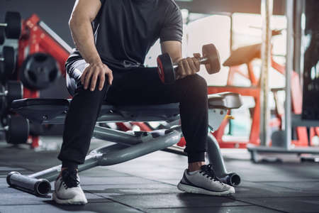 Sportsman doing exercises with dumbbells, strong male keeping fit workout on fitness gym. Motivated moving active healthy lifestyle, Bodybuilding muscle bicep focus.の写真素材