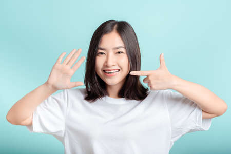 Dental braces of young asian woman wearing braces beauty smile with white teeth increase confidence for healthy on blue background isolated studio shot, Happiness teenager smiling facial expression.の写真素材