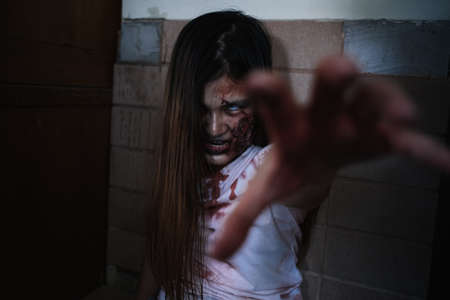 Zombie characters ghost woman bite human in wall horror halloween at nightmare, Female evil screaming monster in night background infected with bleed movie scene film in holiday festival concept.の写真素材