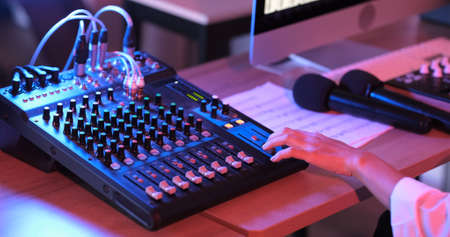 Close up of asian hand producer working at mixing panel in the boutique recording studio. Modern music record studio control desk of digital audio workstation software. Music production concept.