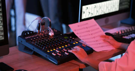 Close up of asian woman hand producer working at mixing panel in the boutique recording studio. Modern music record studio control desk of digital audio workstation software. Music production concept.の写真素材