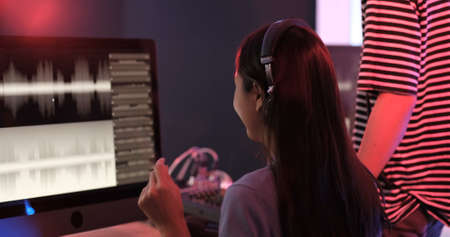 Young asian woman producer and man professional audio engineer working together in music recording studio on a new album, They are working together in the recording studio.の写真素材