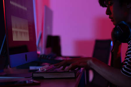Close up of asian man hand producer working at mixing panel in the boutique recording studio. Woman singing has a beautiful smile and emotions in studio on dark background.の写真素材
