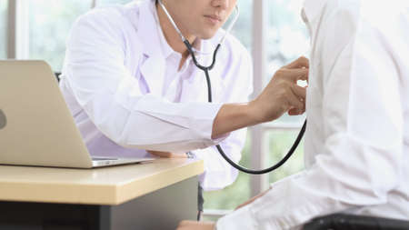 Asian male doctor use stethoscope to examine eldely patient heartbeat. Elderly patients are undergoing physical examination the hospital. Healthcare and Elderly society Concept.の写真素材
