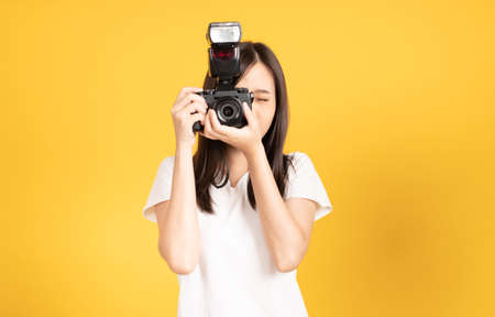 Happy smiling asian young girl photographer and looking viewfinder on retro digital mirrorless photo...
