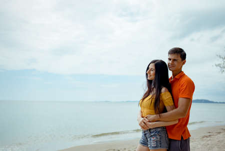 Couple young man and woman dating looking sea on the beach travel happy romantic outdoor enjoying on weekend holidays, Embracing lover together.の写真素材