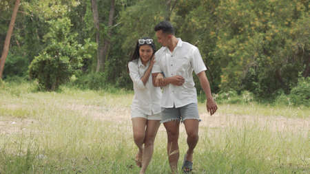 Asian couple young man and woman walking travel in forest happy romantic outdoor enjoying on weekend holidaysの写真素材