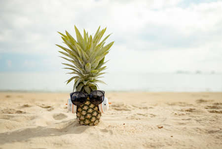 Pineapples in stylish sunglasses on sand travel tropical weekend in holidays summer season resting healthy concept.の写真素材