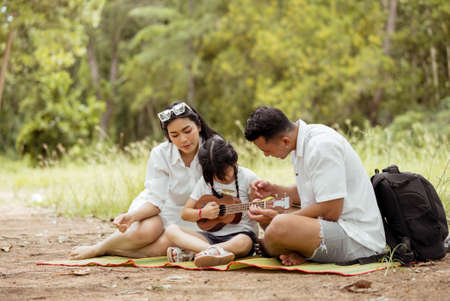 Happy asian family with daughter picnic and travel in forest on weekend holidays relaxation adventure together lifestyle.の写真素材