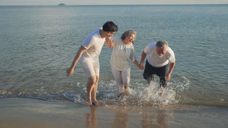 Happiness Asian family son and couple senior elderly retirement resting travel running at sunset beach family together people lifestyle.の写真素材