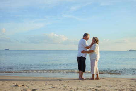 Asian couple senior elder retire resting embrace at sunset beach honeymoon family together happiness people lifestyle with copy space.の写真素材