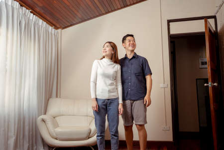 Portrait of two people, Asian man leading her into living room. Surprise in house with noel decoration indoors. Family Holidays Celebration.の写真素材