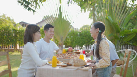 Happy asian grandchild drinking juice grandpa. Multi generation family enjoying meal. They having...