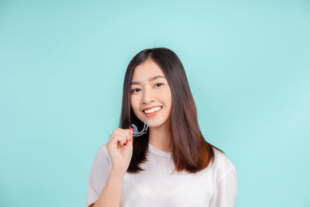 Dental Beautiful smiling of young asian woman with retainer braces glad emotion with white teeth increase confidence for healthy on blue background isolated, Happiness teenager facial expression.の写真素材