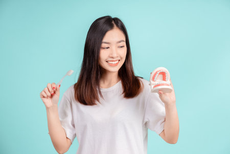 Dental Beautiful smiling of young asian woman teach correct teeth brushing  and toothbrush for white teeth increase confidence for healthy on blue background isolated, Happiness facial expression.の写真素材