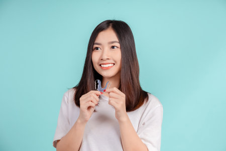 Dental Beautiful smiling of young asian woman with retainer braces glad emotion with white teeth increase confidence for healthy on blue background isolated, Happiness teenager facial expression.の写真素材