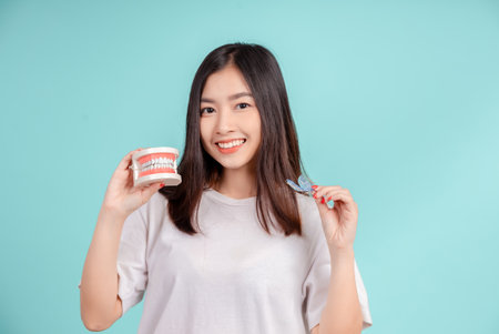 Dental Beautiful smiling of young asian woman with retainer braces glad emotion with white teeth increase confidence for healthy on blue background isolated, Happiness teenager facial expression.の写真素材