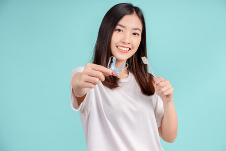 Dental Beautiful smiling of young asian woman with retainer braces and toothbrush for white teeth increase confidence for healthy on blue background isolated, Happiness teenager facial expression.の写真素材