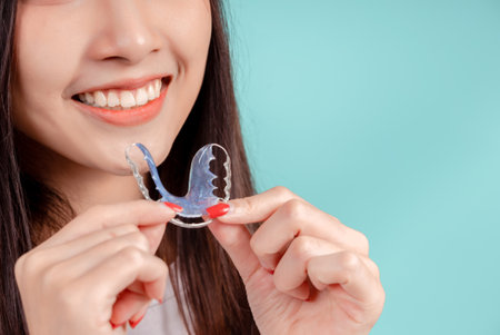 Dental Beautiful smiling of young asian woman with retainer braces glad emotion with white teeth increase confidence for healthy on blue background isolated, Happiness teenager facial expression.の写真素材