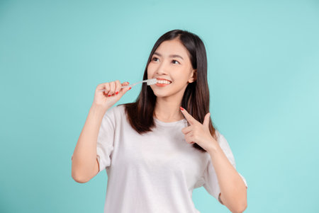 Dental Beautiful smiling of young asian woman teach correct teeth brushing  and toothbrush for white teeth increase confidence for healthy on blue background isolated, Happiness facial expression.の写真素材