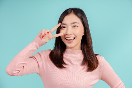 Dental braces of young asian woman wearing retainer braces glad emotion with white teeth increase confidence for healthy on blue background isolated, Happiness teenager smiling facial expression.の写真素材