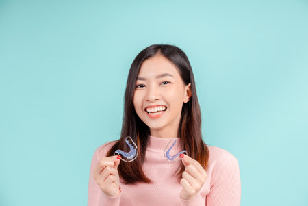Dental Beautiful smiling of young asian woman with retainer braces glad emotion with white teeth increase confidence for healthy on blue background isolated, Happiness teenager facial expression.の写真素材