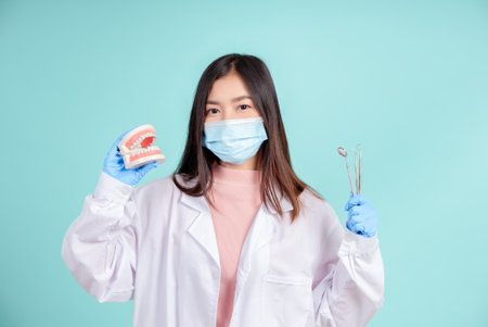 Asian dentists are teaching them how to care for oral and dental care, including after correct orthodontic treatment on blue background isolated studio shot.の写真素材