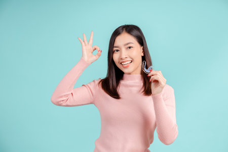 Dental Beautiful smiling of young asian woman with retainer braces glad emotion with white teeth increase confidence for healthy on blue background isolated, Happiness teenager facial expression.の写真素材
