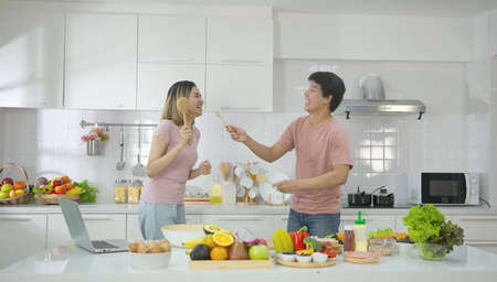 Couple young asian dancing to music together enjoying cooking and smile enjoy life together in home kitchen. Young people relationship and lifestyle.Family couple enjoying together.の写真素材