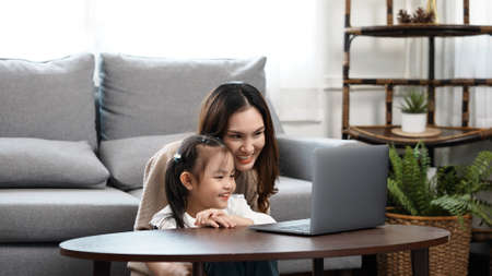 Happy family Mother and daughter watching videe entertainment with laptop computer technology the living room enjoy life at home concept.の写真素材