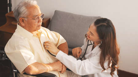 Close up Shot: Female nurse doctor in uniform health check senior grandfather patient at home medical visit, Elderly old male people healthcare support and encouraging the patient in life.の写真素材