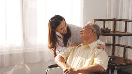 Female nurse doctor in uniform health check senior grandfather patient at home medical visit, Elderly old male people healthcare support and encouraging the patient in life.の写真素材