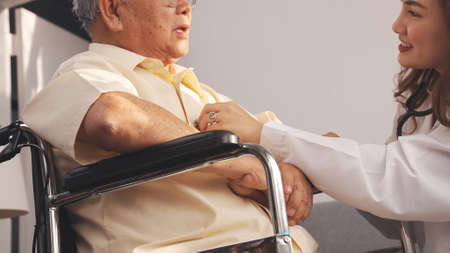 Close up Shot: Female nurse doctor in uniform health check senior grandfather patient at home medical visit, Elderly old male people healthcare support and encouraging the patient in life.の写真素材