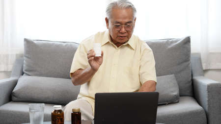 Senior male patient discuss about drug medicine with doctor in online using laptop computer digital technology wifi internet connection, Elderly retired life at home concept.の写真素材