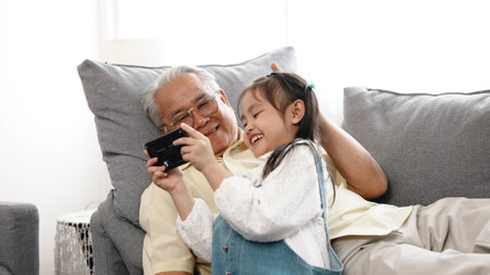 Happy family uncle senior male selfie taking photo with daughter with mobile smartphone on sofa in the living room, Elderly old man patient retired enjoy life concept.の写真素材