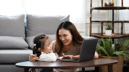 Happy family Mother and daughter watching videe entertainment with laptop computer technology the living room enjoy life at home concept.の写真素材