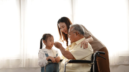 Happy Family Multi-generation Mother and daughter taking care of the senior grandfather in the house, sitting on the wheelchair happiness, Elderly retirement concept.の写真素材