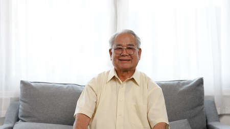 Portrait shot: Smiling of asian senior male enjoy life retirement plan for insurance happy enjoy life siting on sofa in the living room at home, Happiness healthy people elderly concept.の写真素材